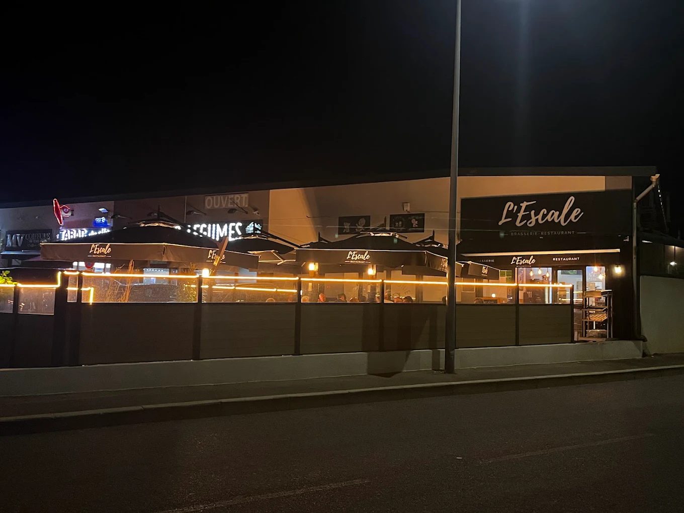 La façade illuminée de L'Escale, brasserie-restaurant, de nuit