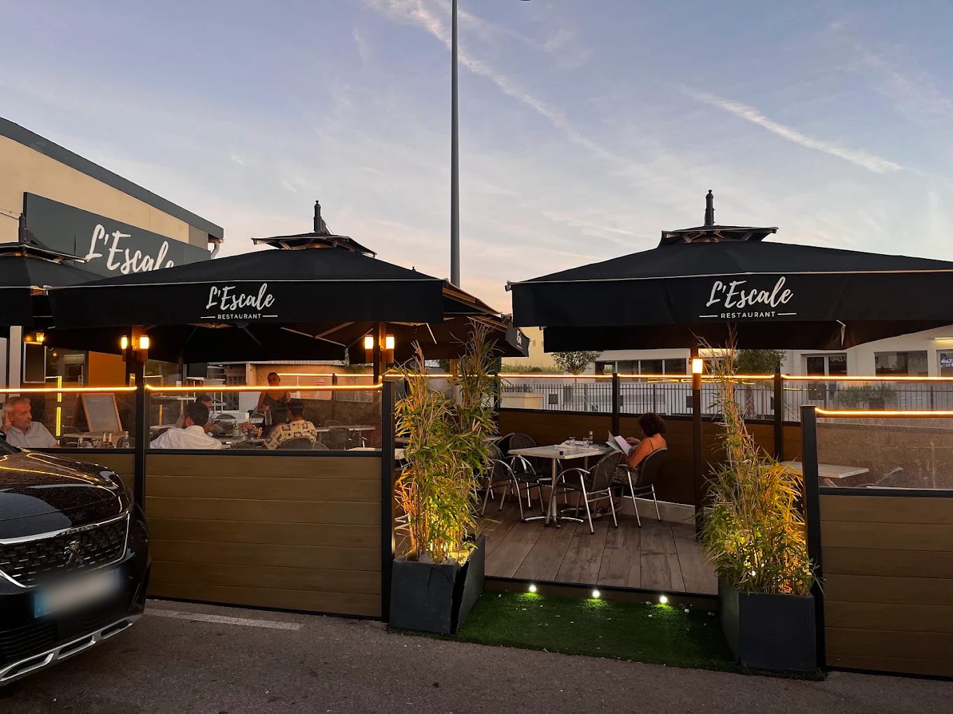 La terrasse de L'Escale au coucher du soleil, sous les parasols noirs du restaurant